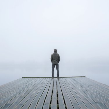 Man stood alone on jetty in fog