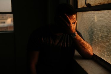 Man by window with head in hand