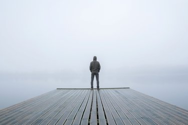 Man stood alone on jetty in fog