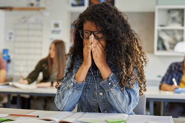 Girl sat at desk with head in hand